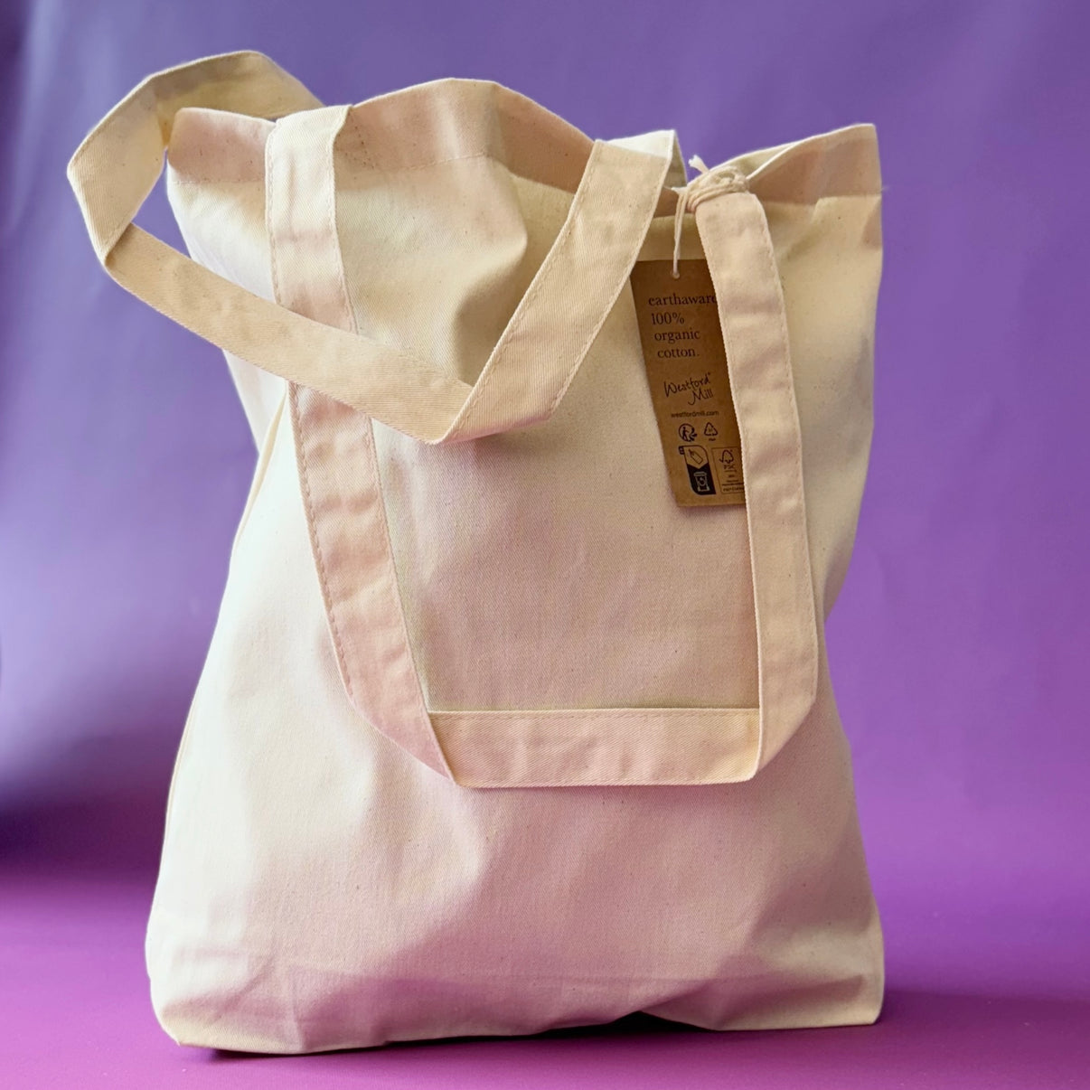 Organic cotton tote bag held to show the size